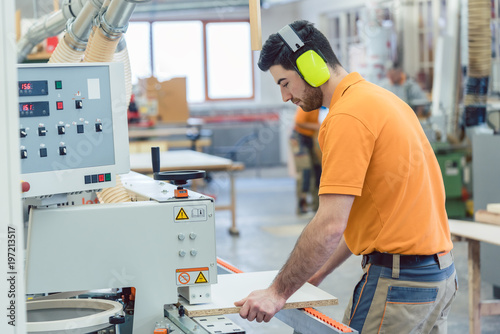 Tischler arbeitet in Möbelfabrik an der Furnier Maschine