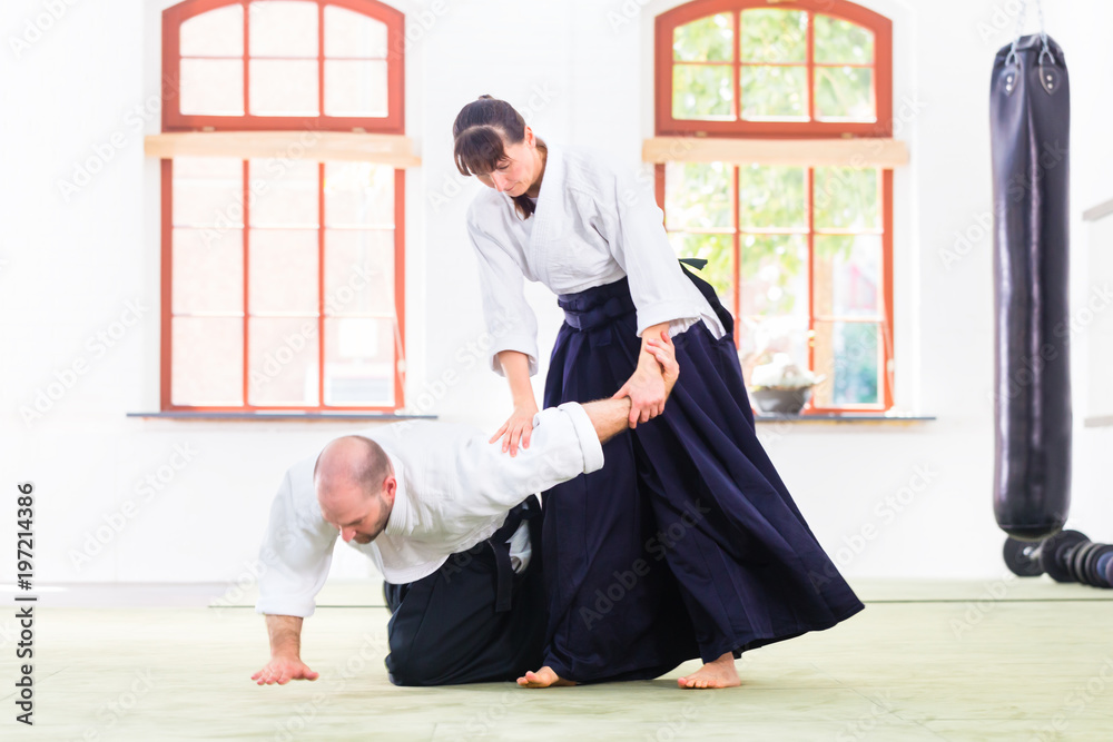 Man and woman fighting at Aikido training in martial arts school Man and woman fighting at Aikido training in martial arts school