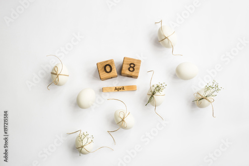 Easter white eggs are minimalistically decorated with twine and gypsophila. With a wooden calendar. 08 April 2018. Easter. Top view, flat lay