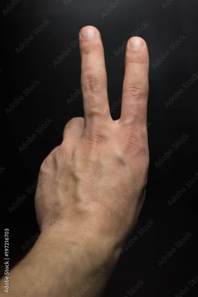 Hand showing victory sing on black background Hand showing victory sing on black background