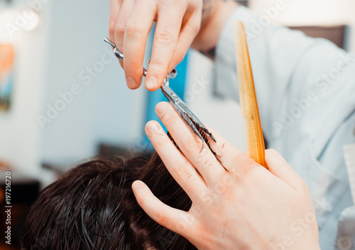 Men's hairstyling and haircutting with hair clipper in a barber shop or hair salon. Bearded brutal man in a barber shop.