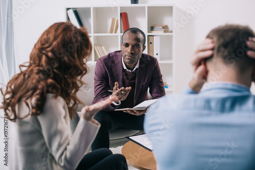 Frustrated divorcing couple and african american counselor in office