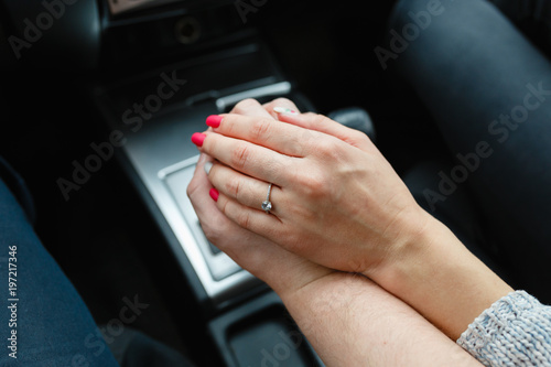 A young couple in love holding hands, holding on the shift lever going into the road trip. A man and a girl go together by car.