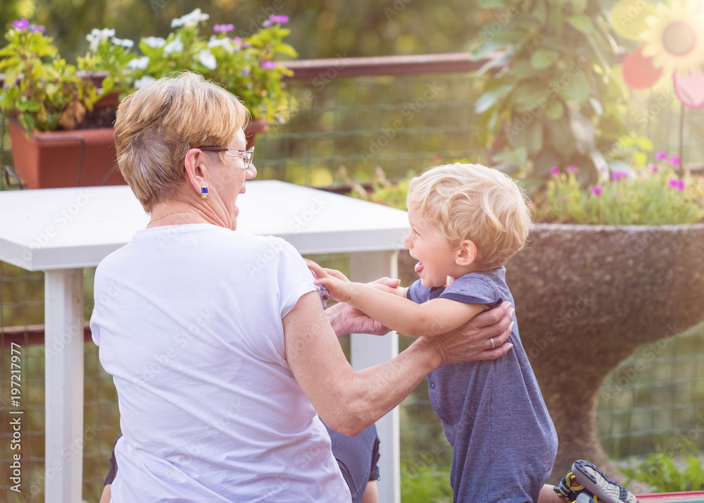 Fototapeta premium Grandmother and grandchild happily play in the garden. Natural light.