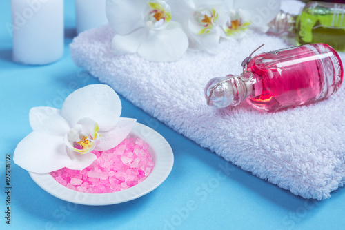 Spa background  flat layout with pink sea salt  candles and aroma oils and beauty care products on a blue background