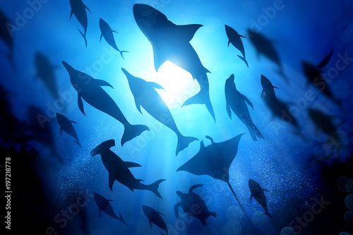 A variety of marine and ocean life silhouettes under the waves including salt water Dolphins, sharks and fish. Mixed media illustration.