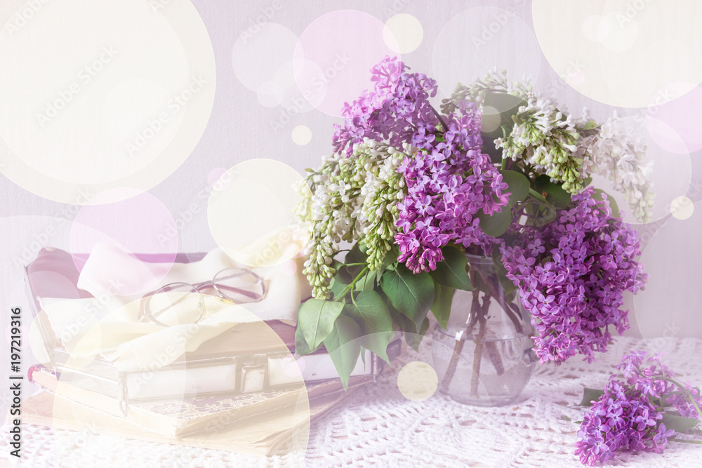 Obraz premium A bouquet of lilac and a vintage handbag, books, glasses on a knitted tablecloth, toning. Sunny summer day.