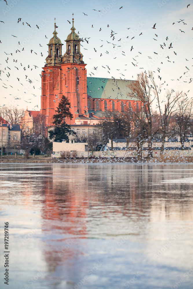 Fototapeta Gniezno, Poland; evening view to the gothic cathedral upon the frozen lake. Winter.