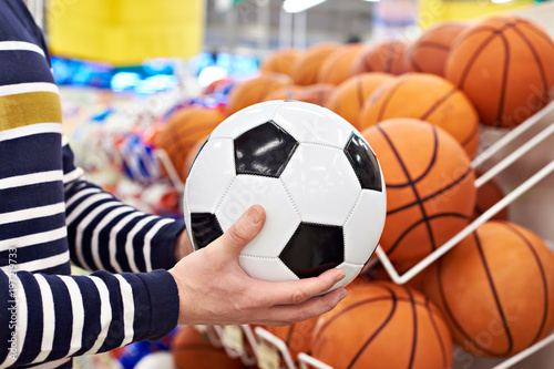 Buyer hands with football and basketball in sports shop photo