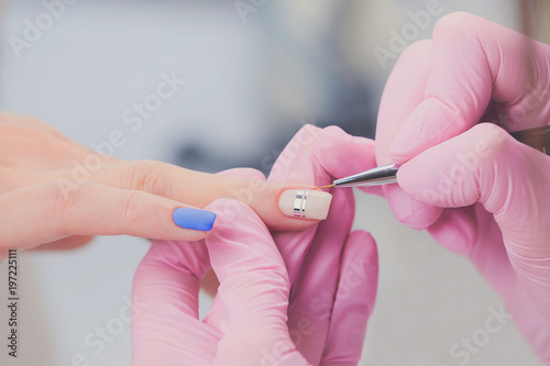 Professional manicure process in beauty salon. Closeup manicurist decoration on female nails. Nail art
