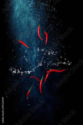 Hot red pepper flakes in the air. Juicy spices on black background