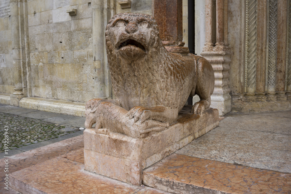Sculpture of lion with pray in front of Duomo in Modena, Italy