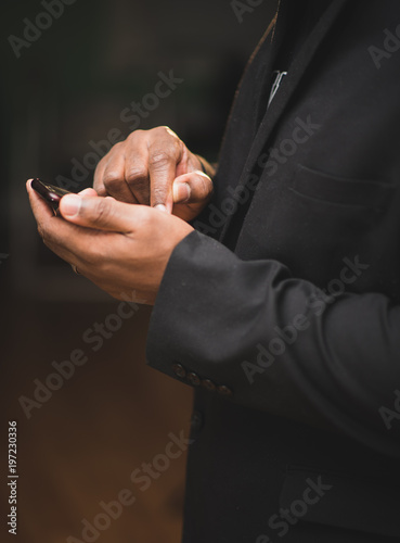 African american man in black suit using mobile device © rohane