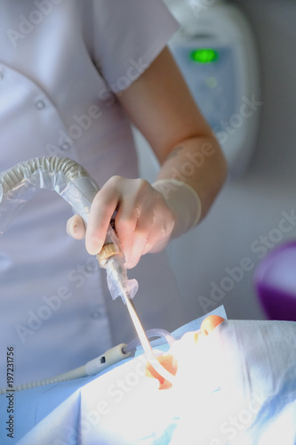 Hands of a dental surgeon in protective gloves with a tool during surgery