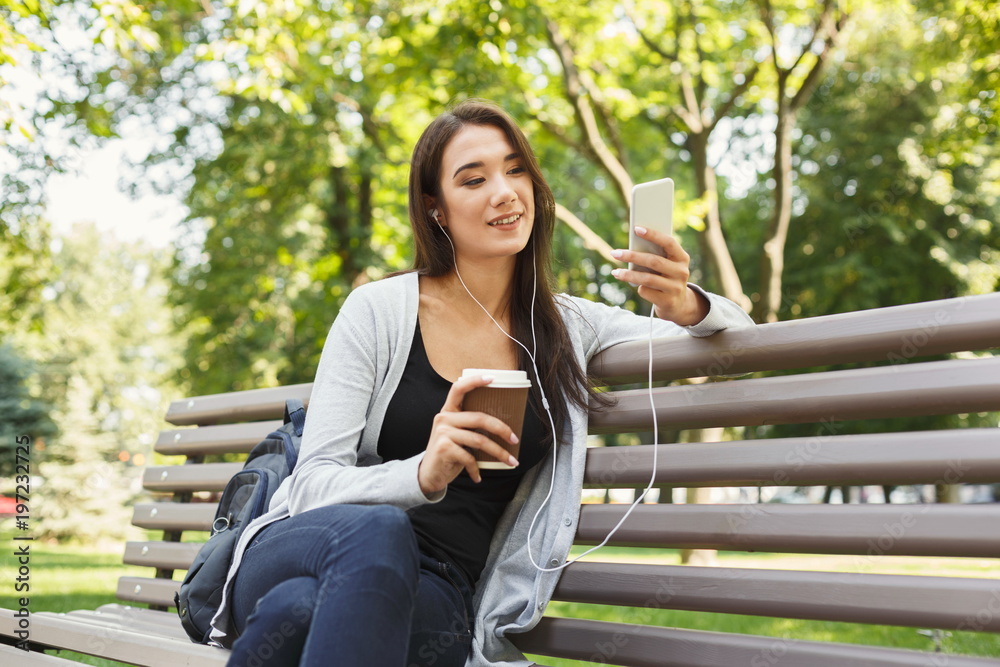 Student sitting in park and using smartphone Student sitting in park and using smartphone
