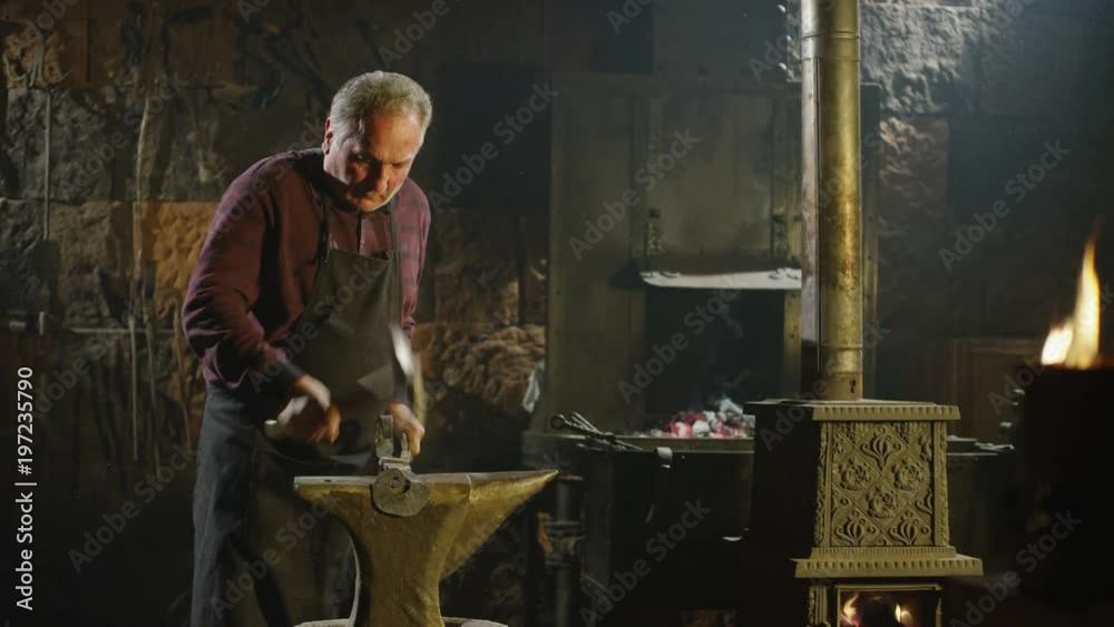 Blacksmith brings dripping hot metal from furnace and he beats a piece of hot metal with a hammer on an anvil. Shot on RED EPIC-W Helium Cinema Camera in Slow Motion. Blacksmith brings dripping hot metal from furnace and he beats a piece of hot metal with a hammer on an anvil. Shot on RED EPIC-W Helium Cinema Camera in Slow Motion.