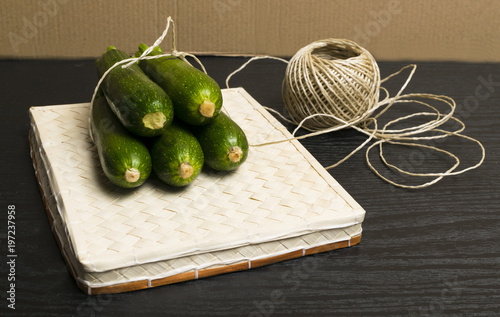 whole mini green zucchini with thread over dark background. photo