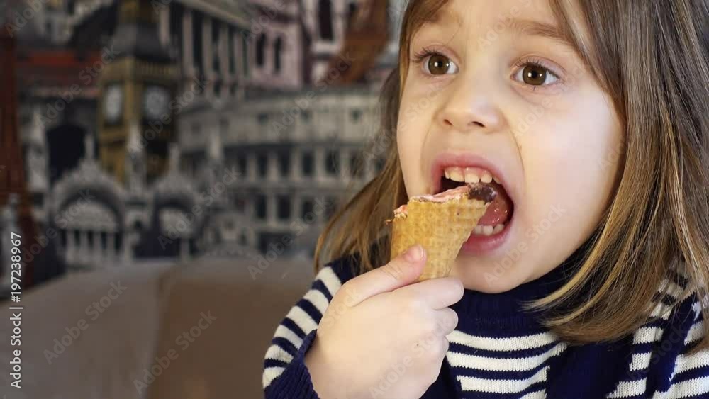 Shooting close-up. A small child, a charming girl 4-5 years old, eating ice cream in a waffle cup and watching TV. Shooting close-up. A small child, a charming girl 4-5 years old, eating ice cream in a waffle cup and watching TV.