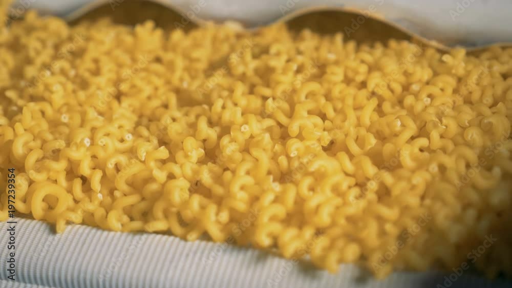 Close up of small yellow pieces of spiral macaroni moving down. Pasta, macaroni, noodle, spaghetti production line. Close up of small yellow pieces of spiral macaroni moving down. Pasta, macaroni, noodle, spaghetti production line.