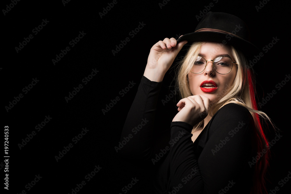Sexy blonde model wearing black blouse, hat and glasses, posing in the shadow Sexy blonde model wearing black blouse, hat and glasses, posing in the shadow