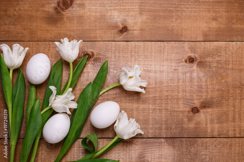 Tulips flowers and eggs decoration over wooden background. Top view, text space