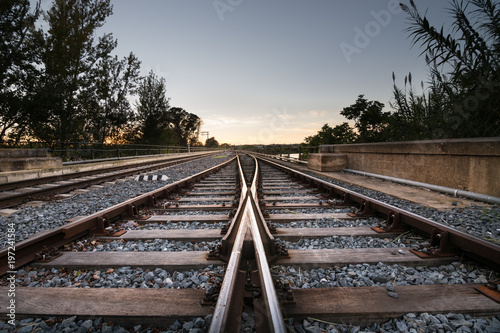 Rails train towards the infinite in sunset