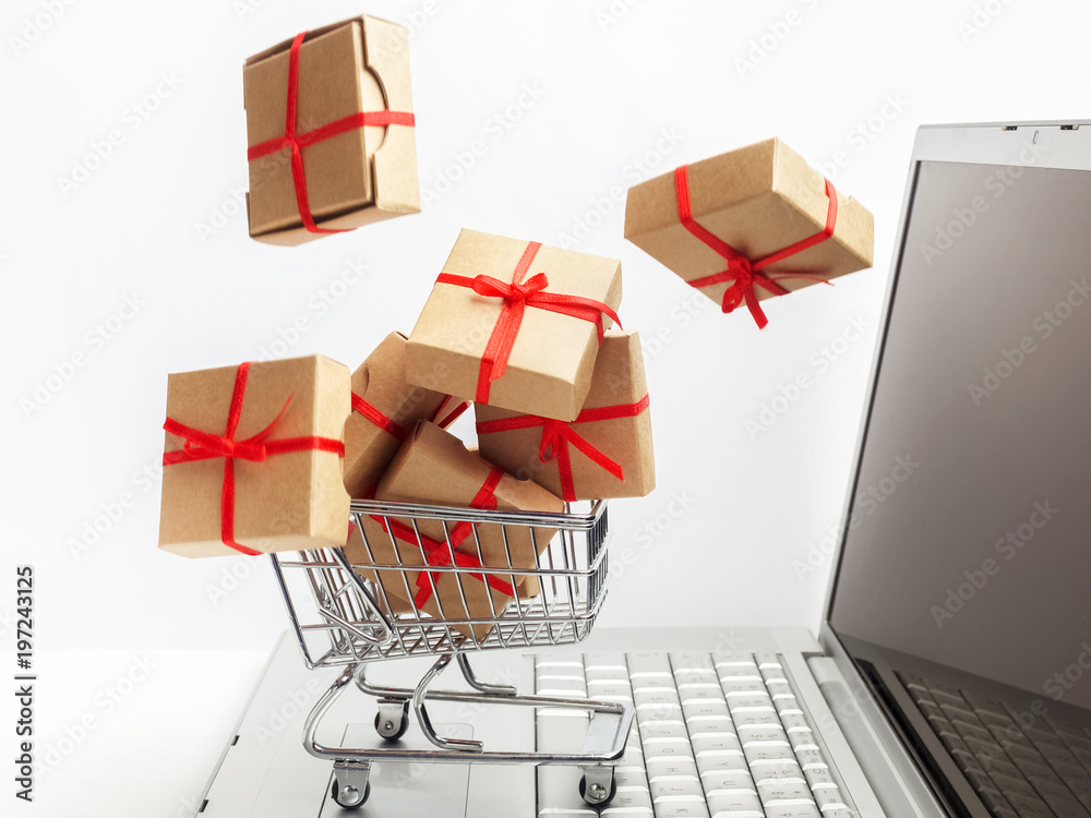 Paper boxes in a shopping cart on a laptop keyboard. Ideas about e-commerce, a transaction of buying or selling goods or services online.