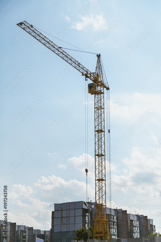 Lifting tower crane against cloudy sky background
