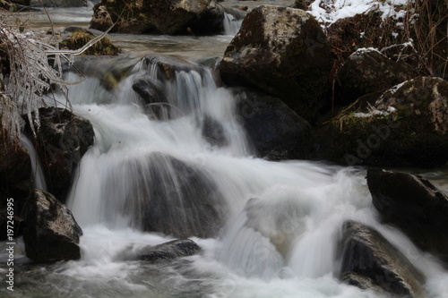 Rivi  re ou ruisseau de montagne d  valant des rochers en cascade fig  e par l hiver et la glace. Branchages congel  s. Vitesse lente. 