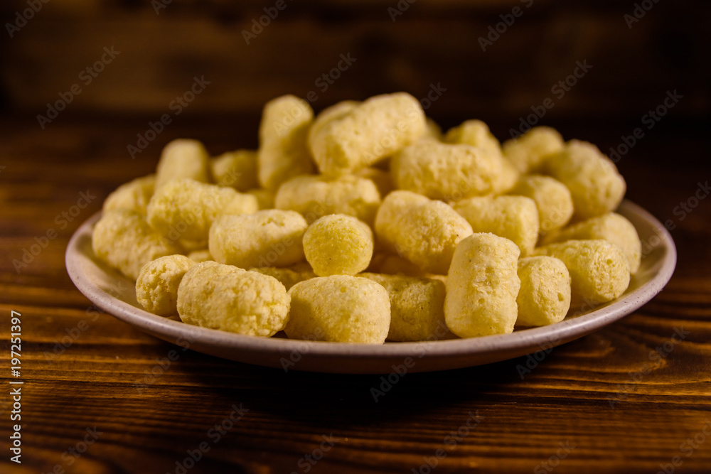 Ceramic plate with corn sticks on wooden table Ceramic plate with corn sticks on wooden table
