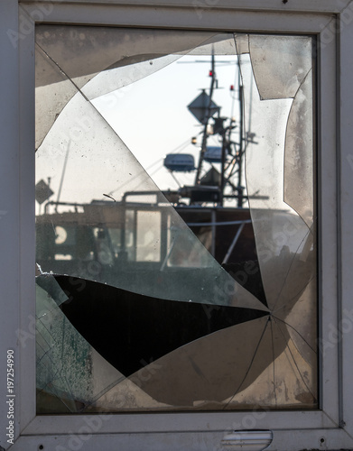 Looking through a battered windowpane at a fishing boat. Focus on the disc. Concept: vacation and travel or crime