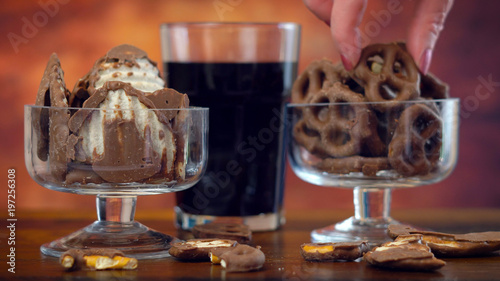 Sweet and salty chocolate covered salt and vingear potato chips and pretzels with cola drink, on rustic wood background. photo