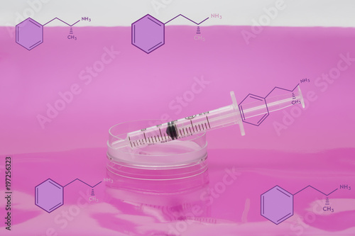 Drug addicition concept. Syringe in petri dish and structural formula of amphetamine photo