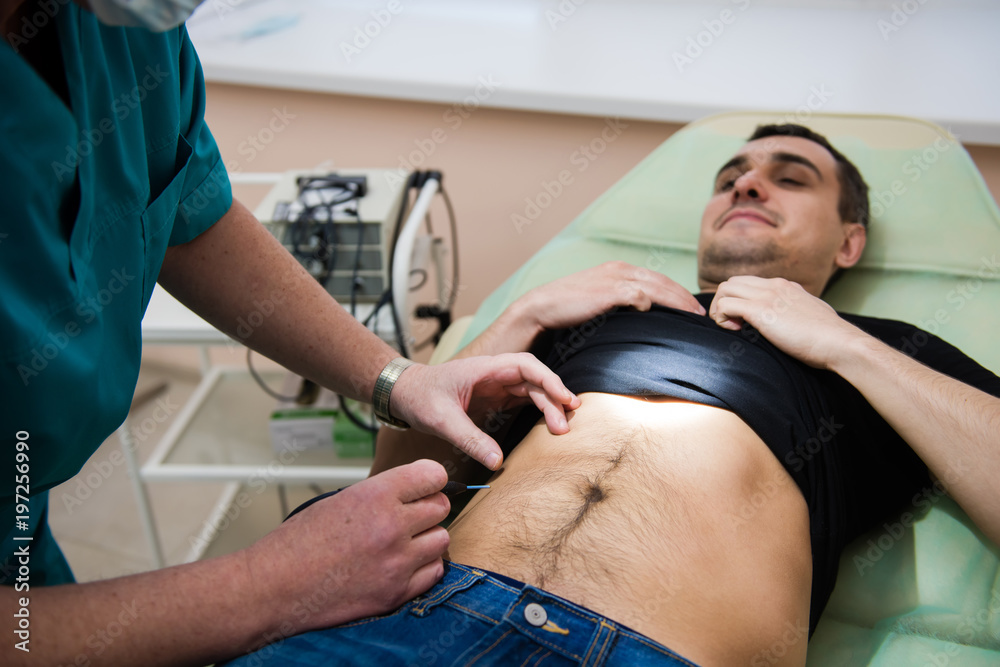 Obraz premium Man checkup stomach in clinic couch