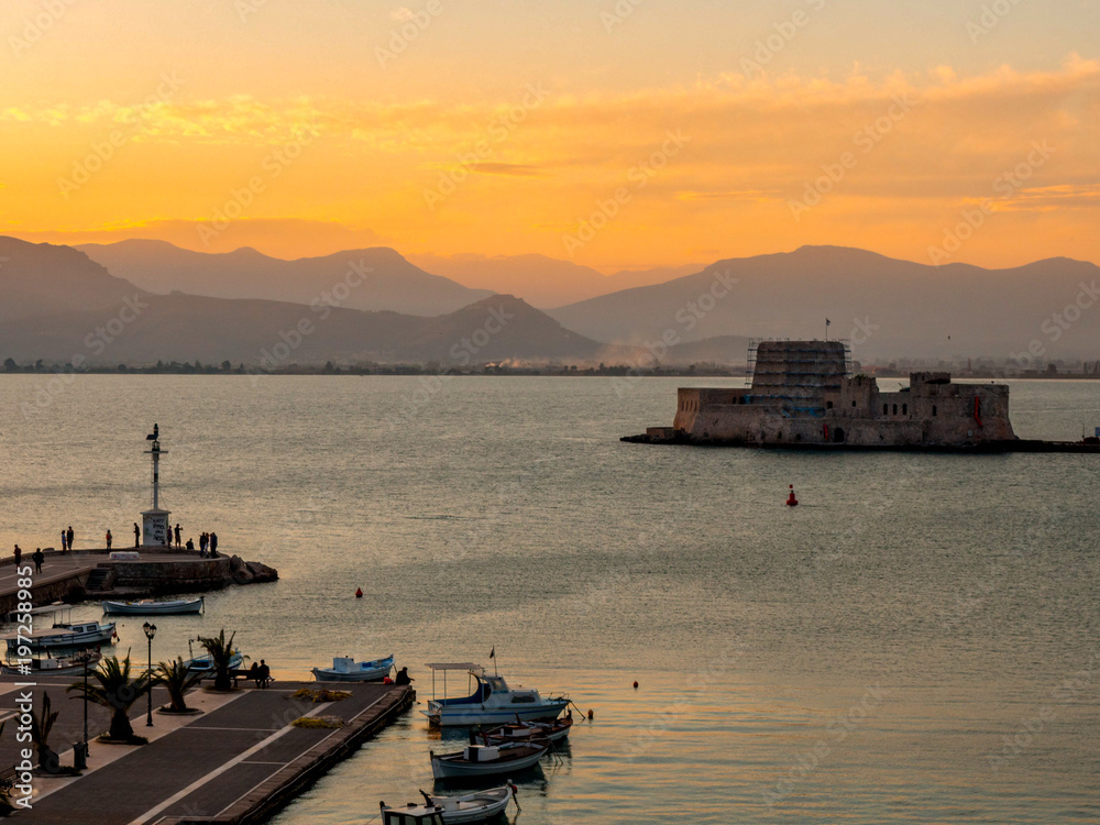 A panoramic view of the old harbour of Nafplio with the historical water castle of Bourtzi in the middle in sunset