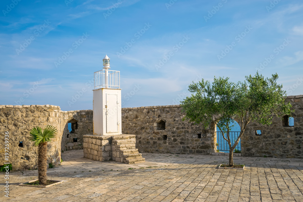 White lighthouse in the old fortress provides safe navigation of ships.