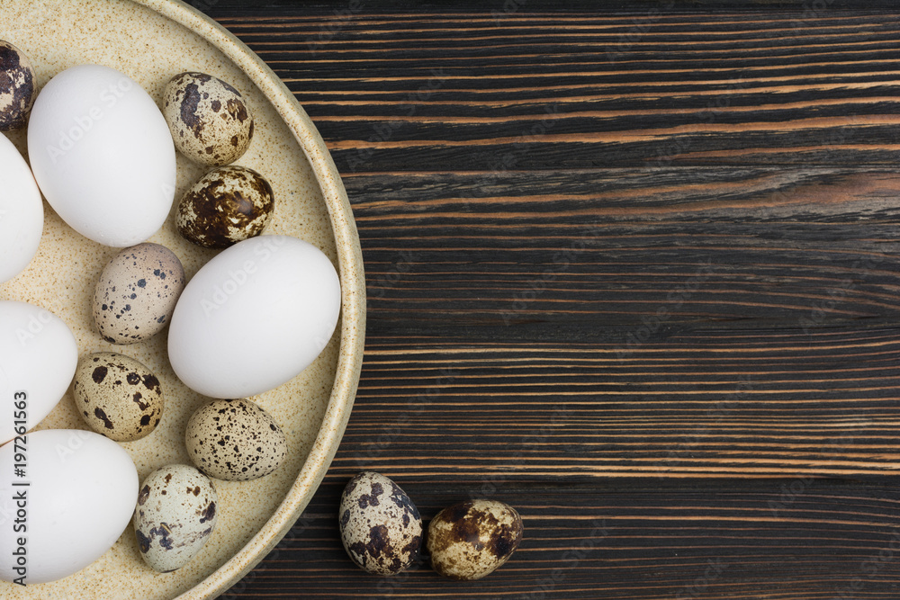 Easter concept. White chicken eggs and quail eggs on wood background on a plate close up. Flat lay. Minimal concept. Top view. Design, visual art. Easter concept. White chicken eggs and quail eggs on wood background on a plate close up. Flat lay. Minimal concept. Top view. Design, visual art.