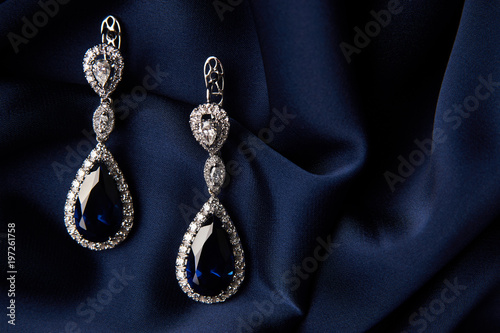Fotografie Pair of platinum earring with sapphire on blue satin background