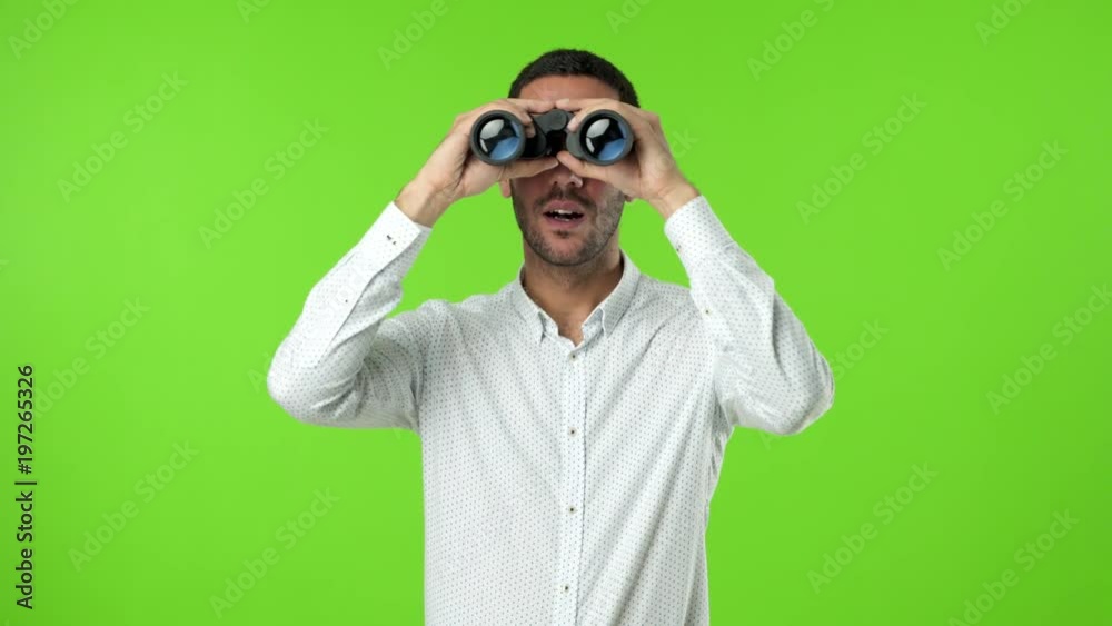 Concentrated young man using a binoculars Concentrated young man using a binoculars