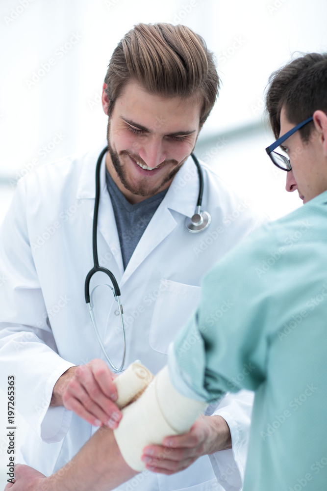Orthopedist applying bandage onto patient's arm Orthopedist applying bandage onto patient's arm