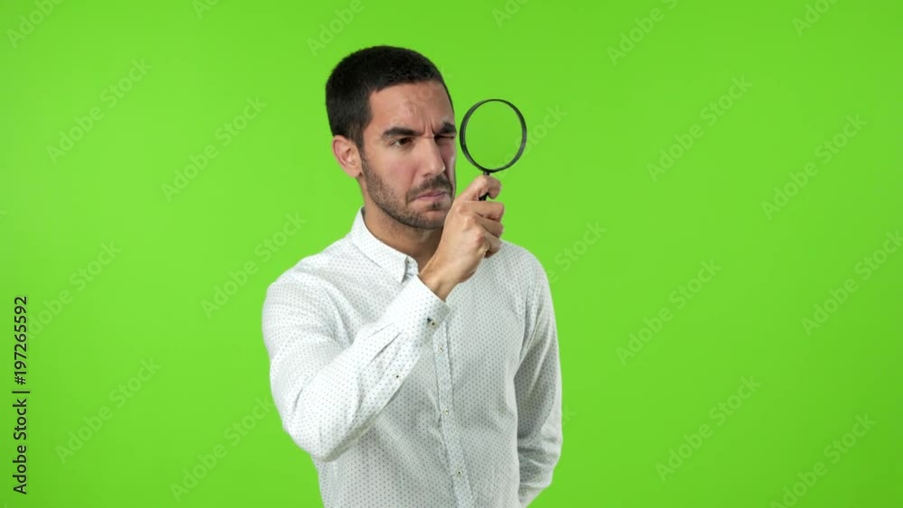 Concentrated young man using a magnifying glass Concentrated young man using a magnifying glass