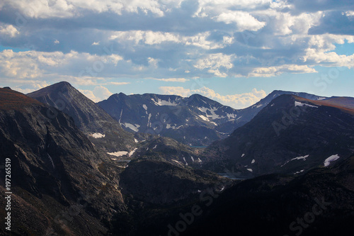Snow capped mountaintops with lakes, ponds, blue sky, white cumulus clouds in Rocky Mountain National Park, Colorado, USA