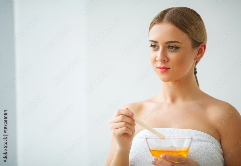 Women hold orange paraffin wax bowl. Woman in beauty salon Women hold orange paraffin wax bowl. Woman in beauty salon