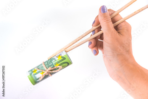 Woman is save pack of one hundred euro banknotes tied up with a rope and hold them with chinese sticks isolated on white background