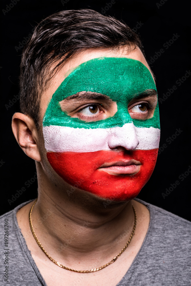 Portrait of handsome man face supporter fan of Iran national team with painted flag face isolated on black background. Fans emotions. Portrait of handsome man face supporter fan of Iran national team with painted flag face isolated on black background. Fans emotions.