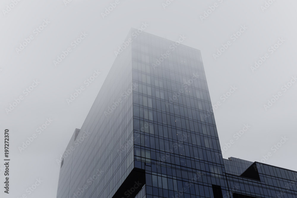 Tower of modern skyscraper glass building in fog or mist Tower of modern skyscraper glass building in fog or mist
