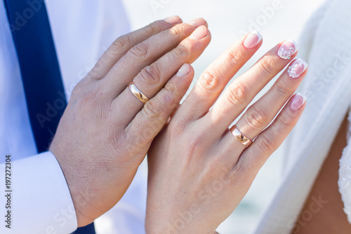 Couple holding hands with wedding rings