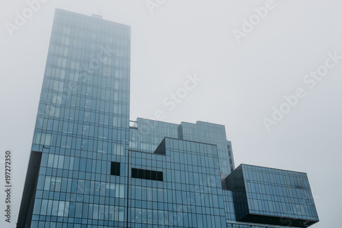 Tower of modern skyscraper glass building in fog or mist