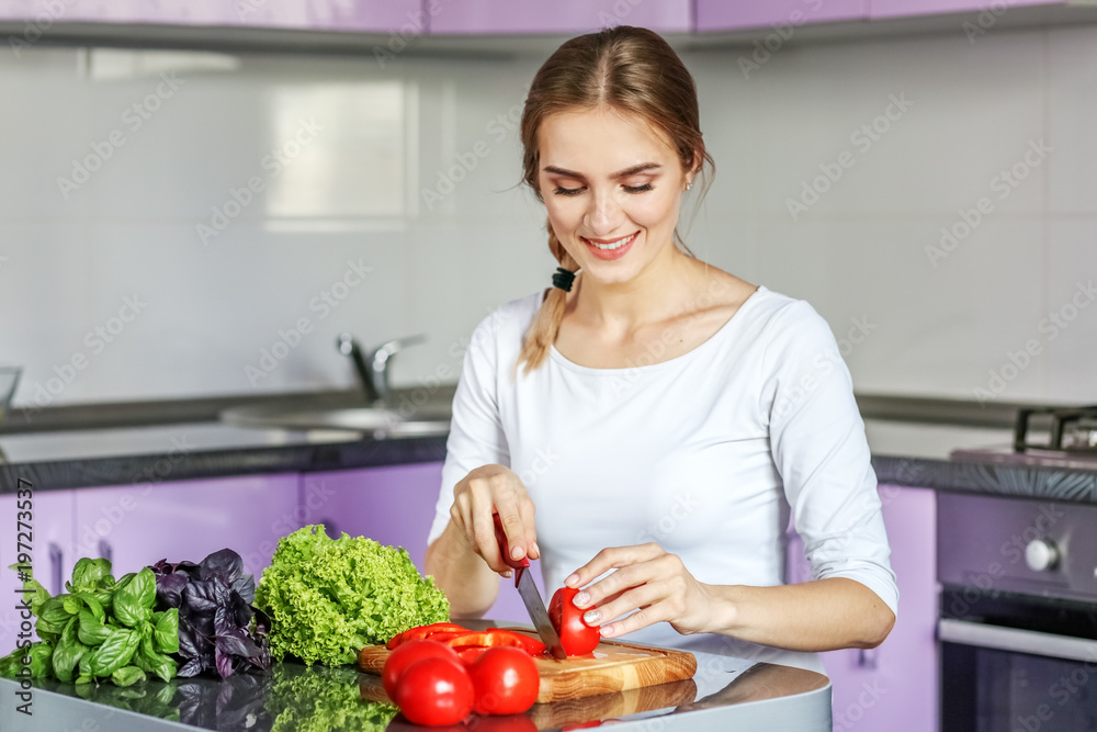 Young happy woman is preparing a delicious lunch in the kitchen. Vegetarian. The concept is healthy food, diet, vegetarianism, weight loss.