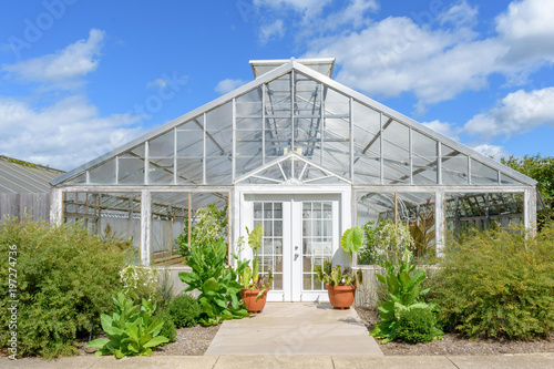 White greenhouse against blue sky with fluffy white clouds